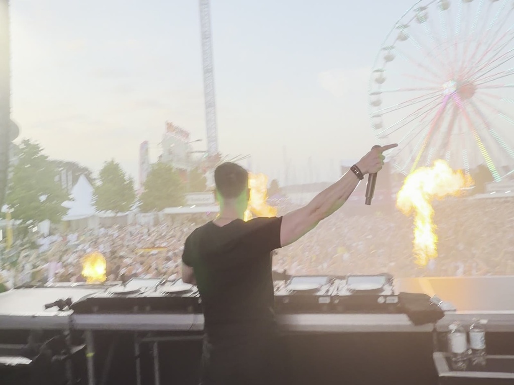 TISCORE performing on a festival mainstage in front of a daytime crowd