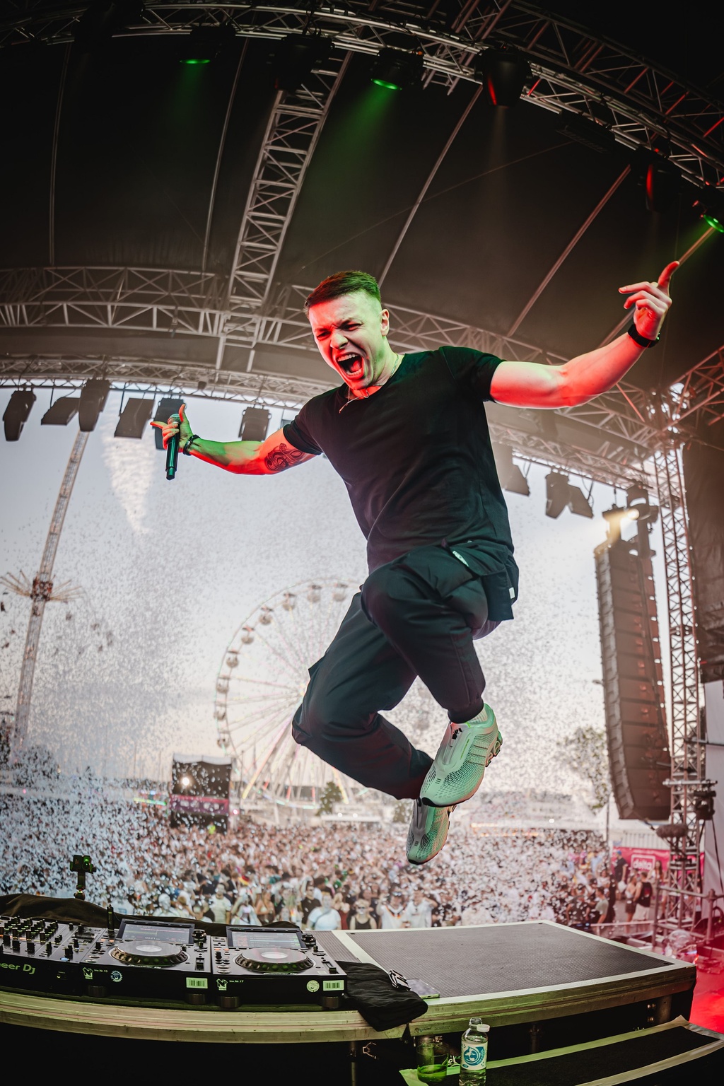 TISCORE jumping off the DJ booth during a festival set in front of thousands of fans.